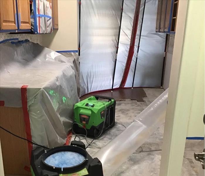 SERVPRO air scrubbers and dehumidification erected in kitchen whose openings, cabinets, microwave, and counters are sealed wi