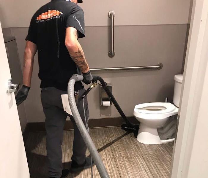 SERVPRO tech holding water removal wand in commercial restroom